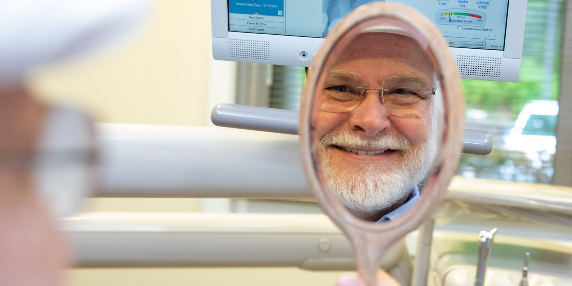 patient looking in the mirror happy after smile makeover Waterford, CT